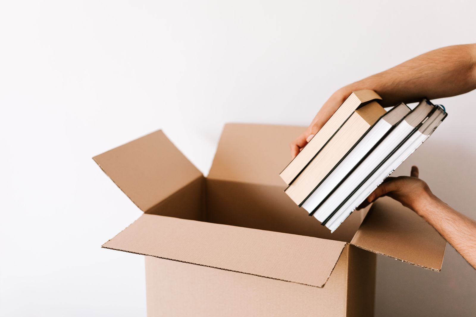 Hands placing a stack of books into a cardboard box